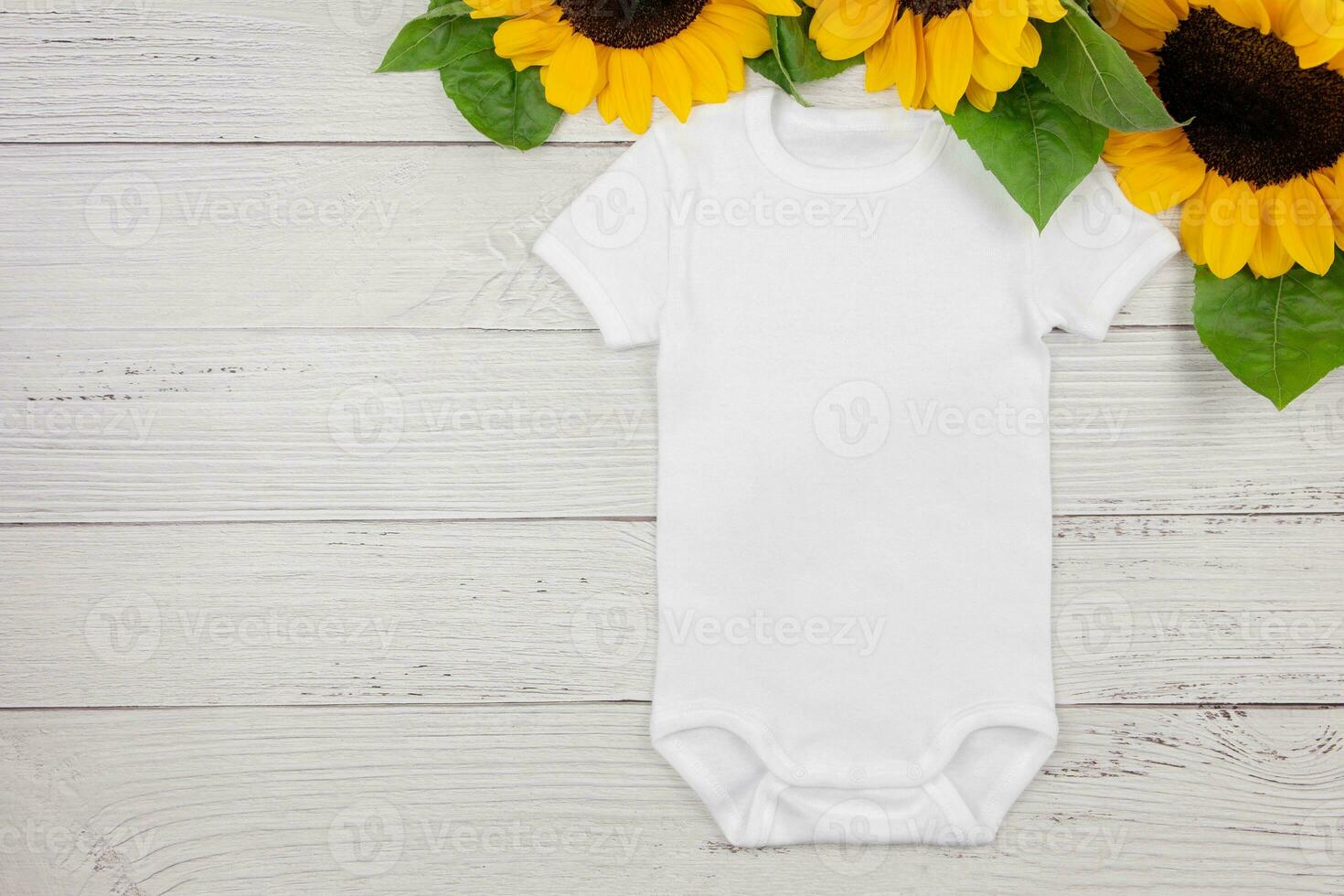 White baby girl or boy bodysuit mockup flat lay with sunflowers on white wooden background. Design onesie template, print presentation mock up. Top view. photo