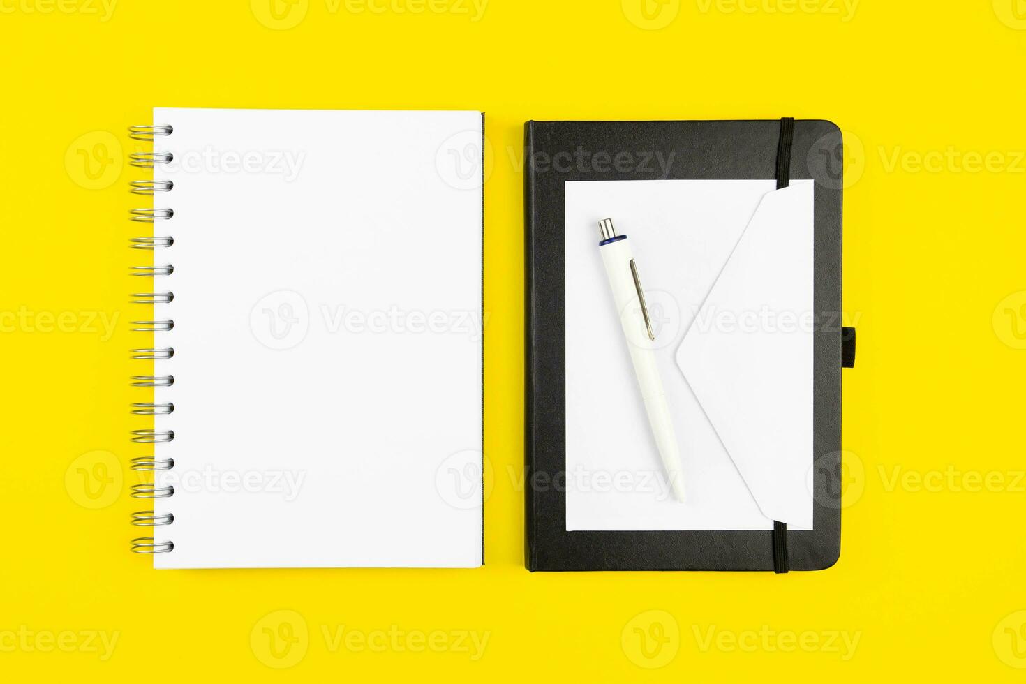 Modern office workplace flat lay with blank paper notebook mockup, envelope and pen on yellow background. Top view. Copy space. photo
