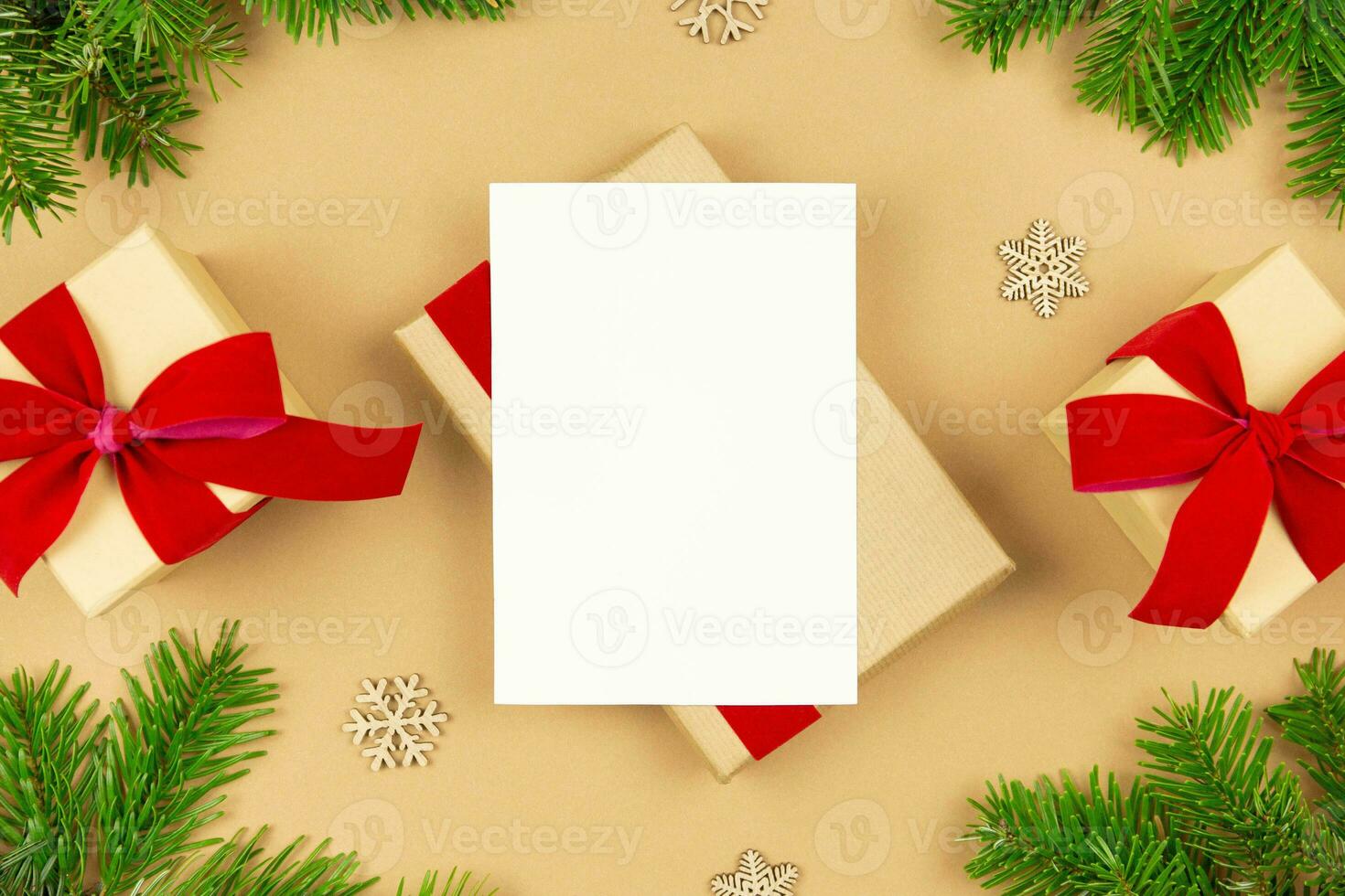 Christmas greeting card mockup and wrapped gift boxes with red ribbon and christmas tree branches decoration on paper background. Festive flat lay styled template composition. Top view. photo