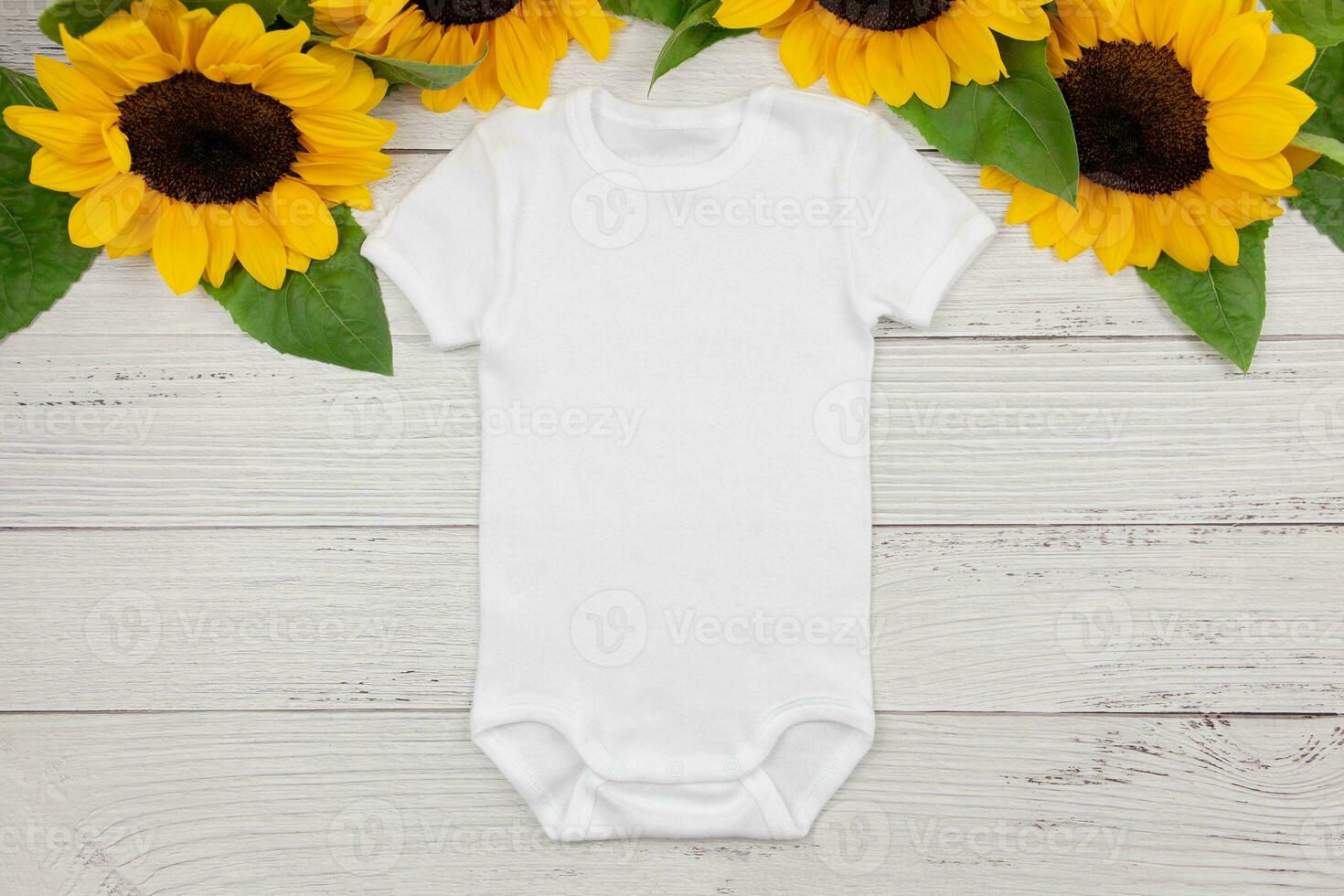 White baby girl or boy bodysuit mockup flat lay with sunflowers on white wooden background. Design onesie template, print presentation mock up. Top view. photo