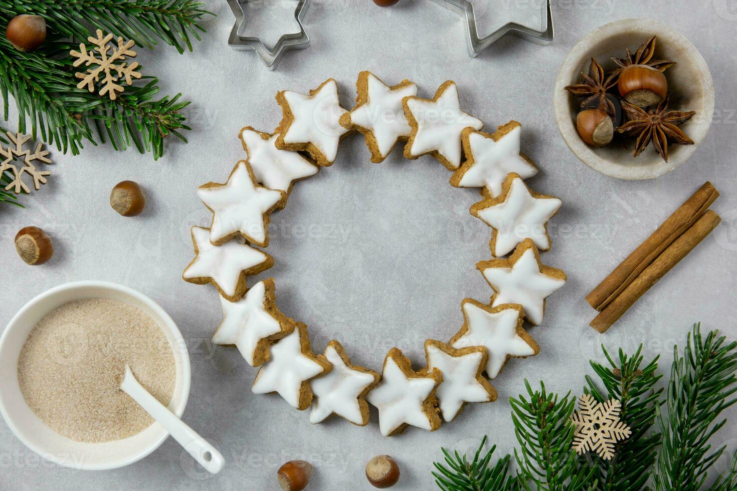 Navidad tradicional alemán guirnalda galletas, canela estrellas con avellanas, decoración y árbol ramas en un ligero hormigón antecedentes. parte superior vista. foto