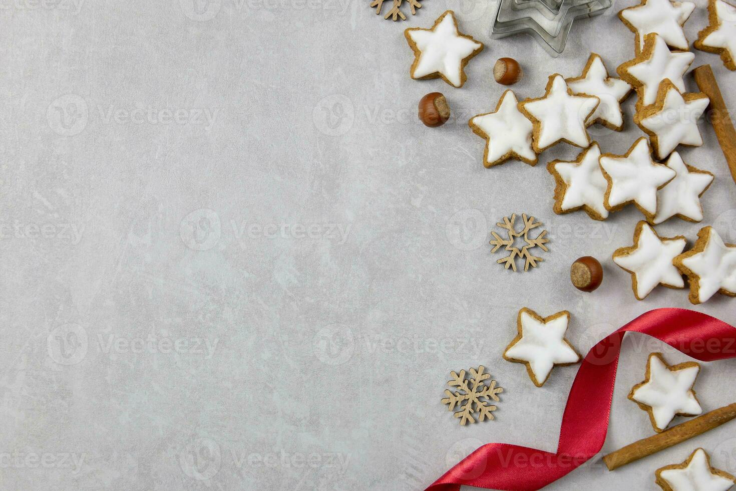 Christmas traditional German cookies, cinnamon stars with hazelnuts, decoration and tree branches on a light concrete background. Top view. Copy space. photo