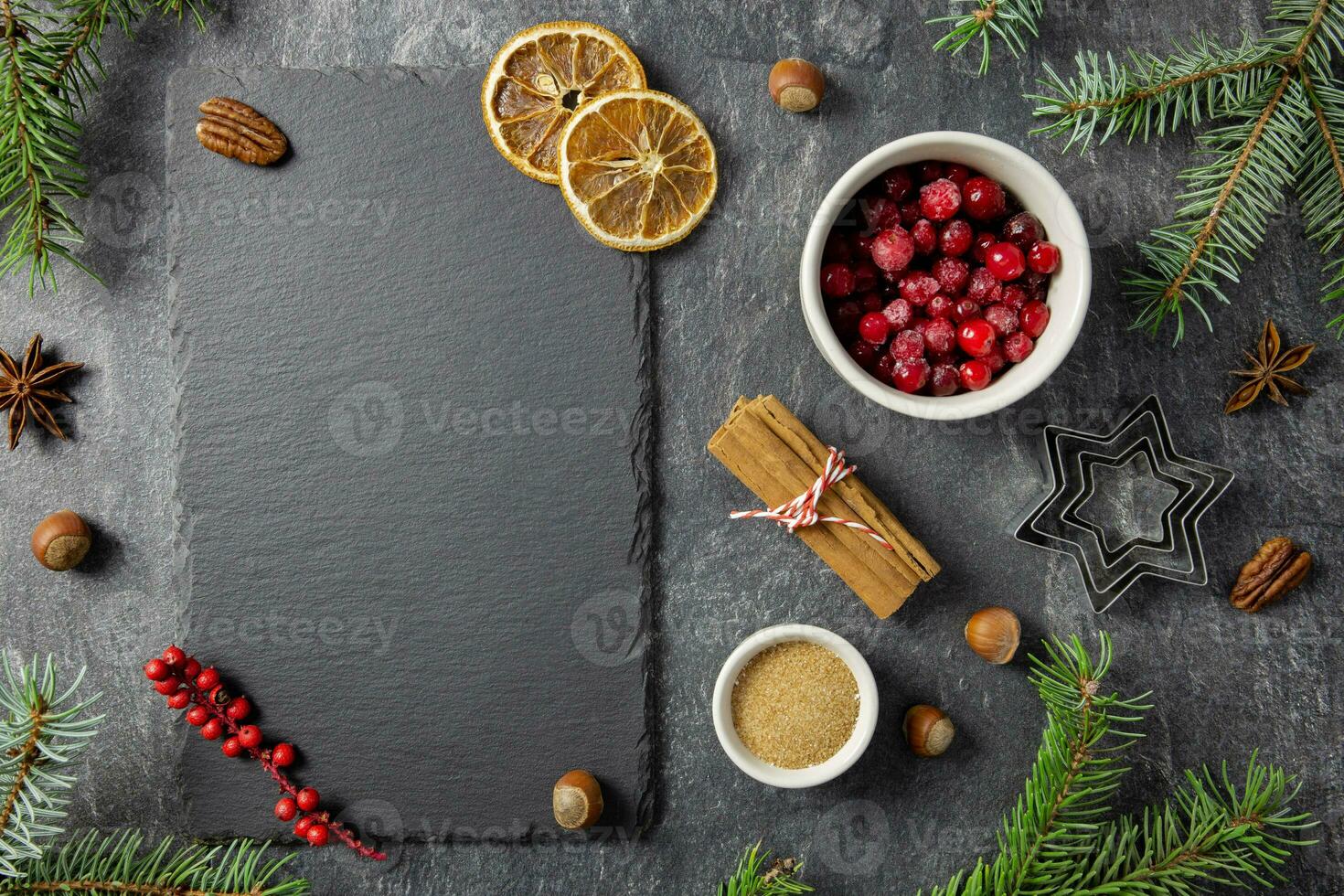 Culinary background with christmas winter spices and ingredients for baking on dark stone table with a black slate, chalkboard mockup for your text. Top view. Copy space. photo