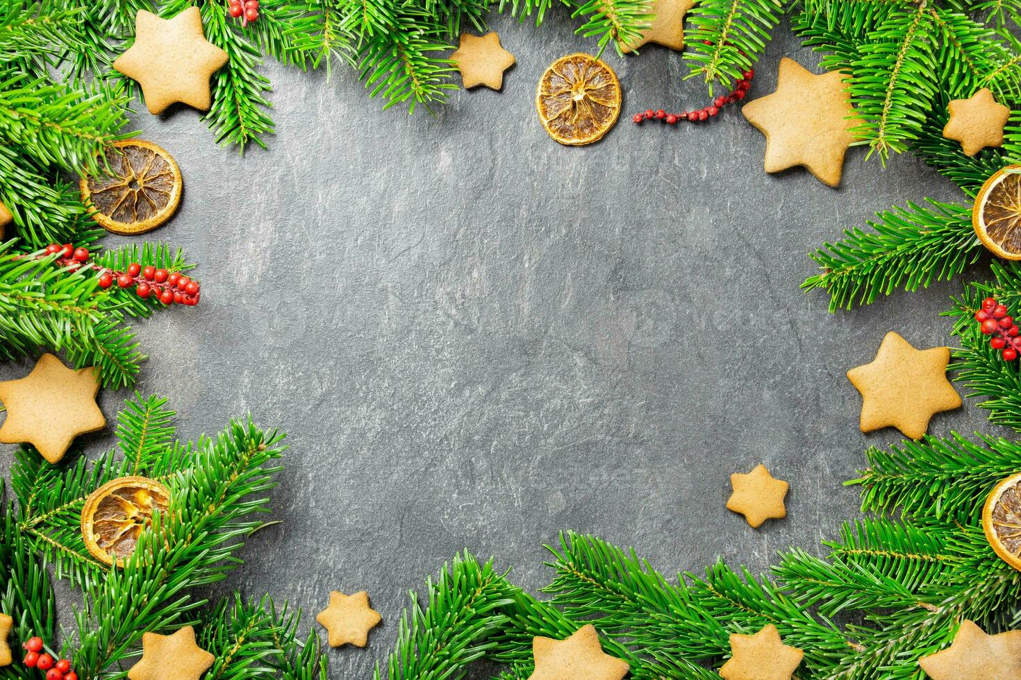 Christmas traditional gingerbread stars with decoration, spices and christmas tree branches on a dark stone background. Top view. Copy space. photo