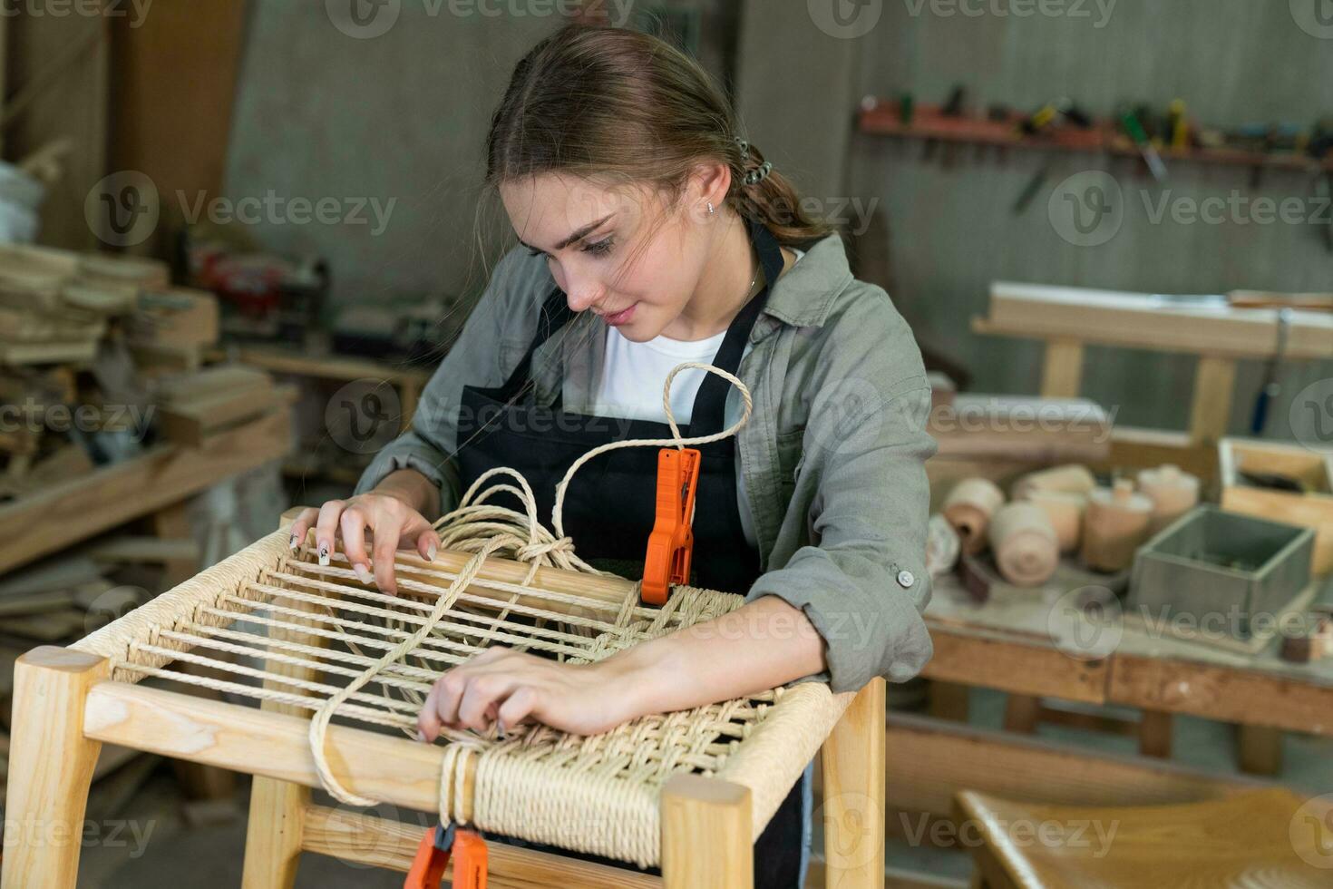 Attractive smiling beautiful woman Warm toned portrait of carpenter building designer wooden furniture hand made chair in workshop, copy space photo