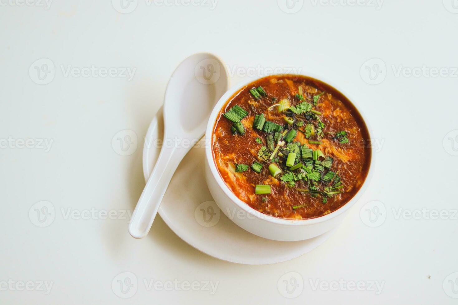 Homemade tomato soup in a white bowl with saucer. Side view isolated on a white background. photo