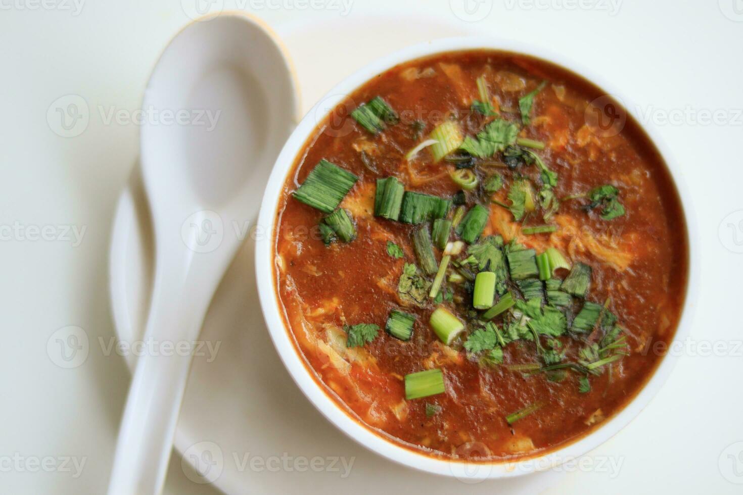 Homemade tomato soup in a white bowl with saucer. Side view isolated on a white background. photo