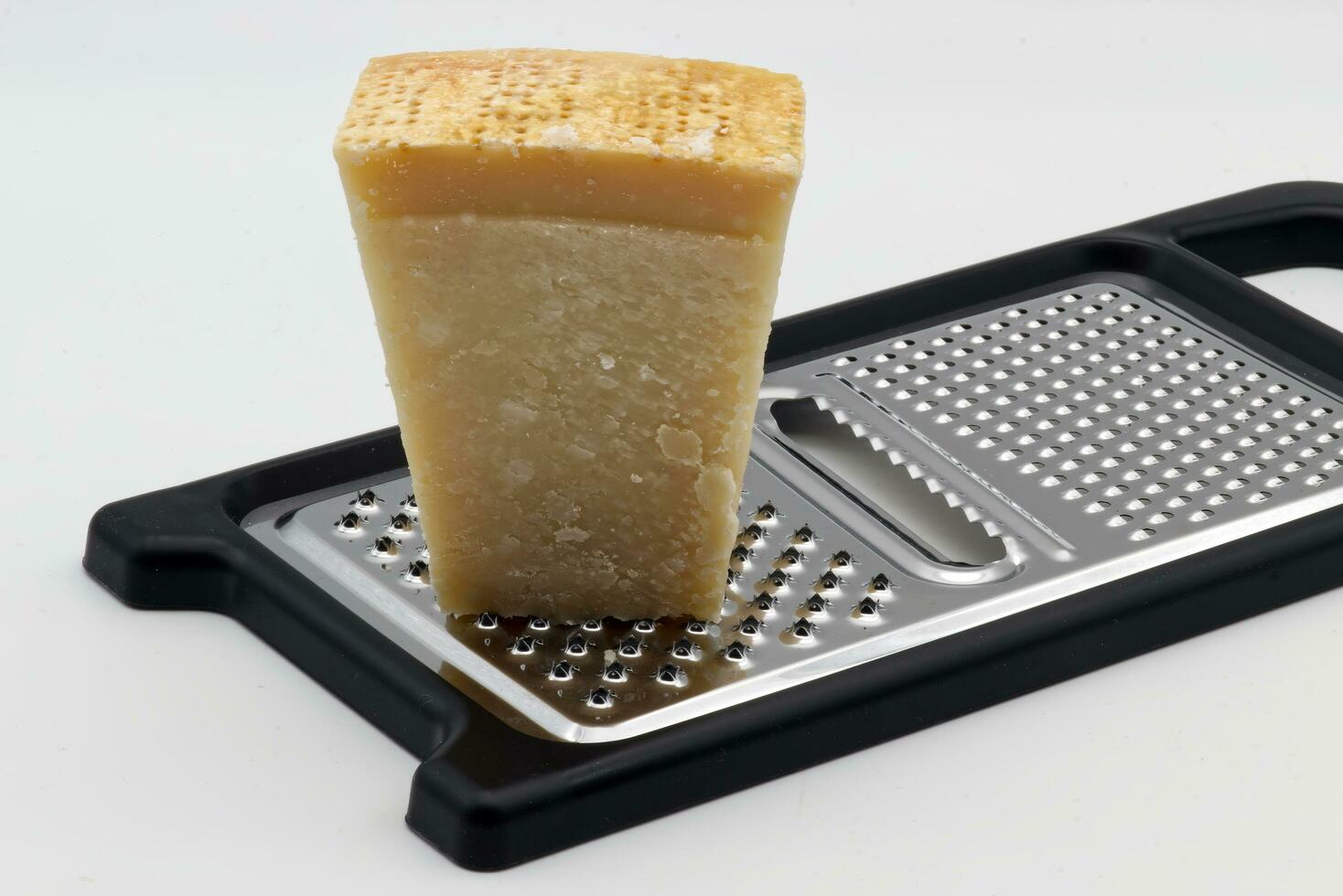 Metal grater with Parmigiano Reggiano cheese isolated on white background. photo