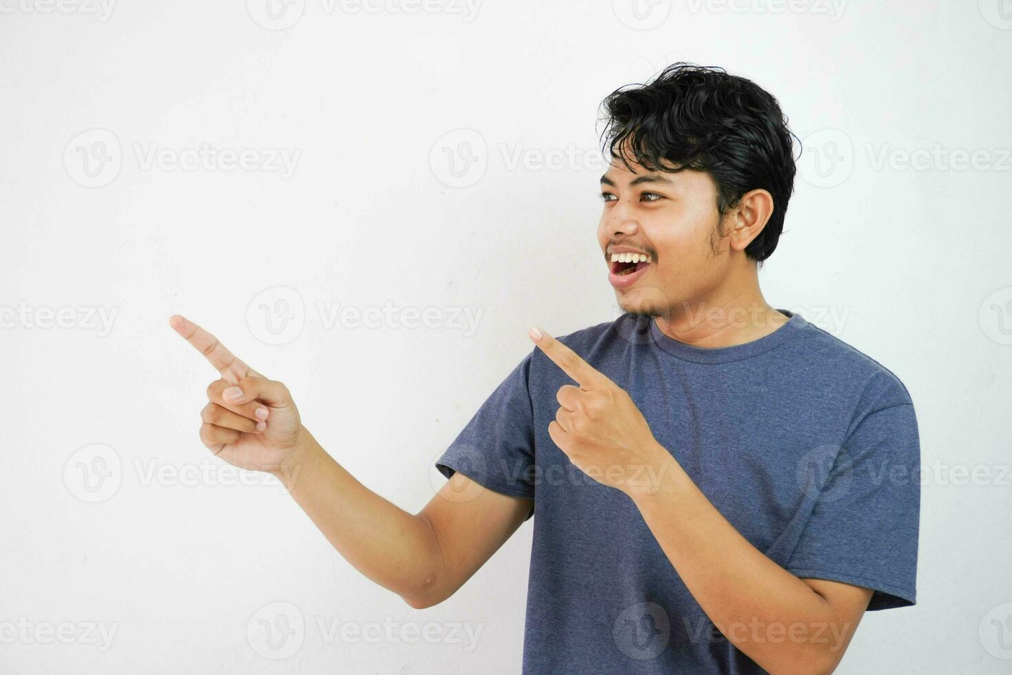 Smiling or happy handsome young Asian man with his finger pointing isolated on white background with copy space photo