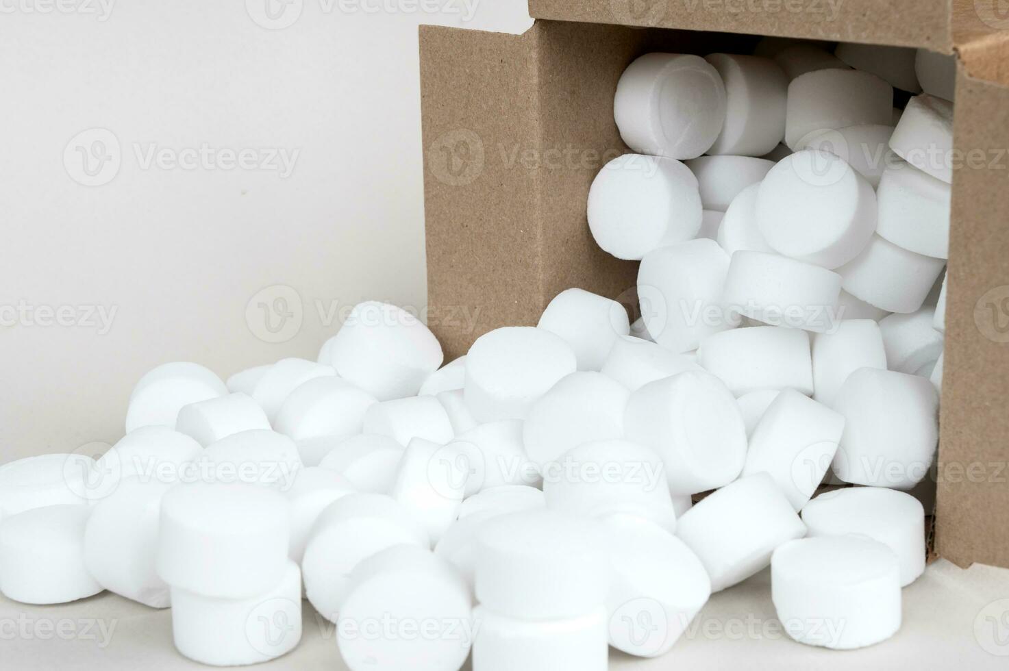 Lying part of a box with scattered pressed dishwasher salt side view close-up. Place for text photo
