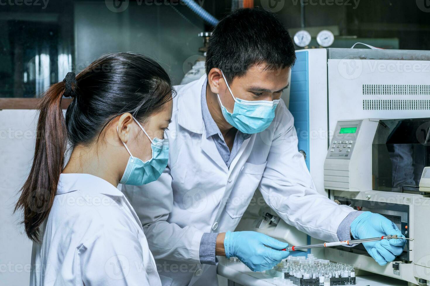 The male researcher prepares a column chromatography cartridge of the Liquid Chromatography mass spectrometry LC-MS instrument to analyze and train a female scientist to use the instrument. photo