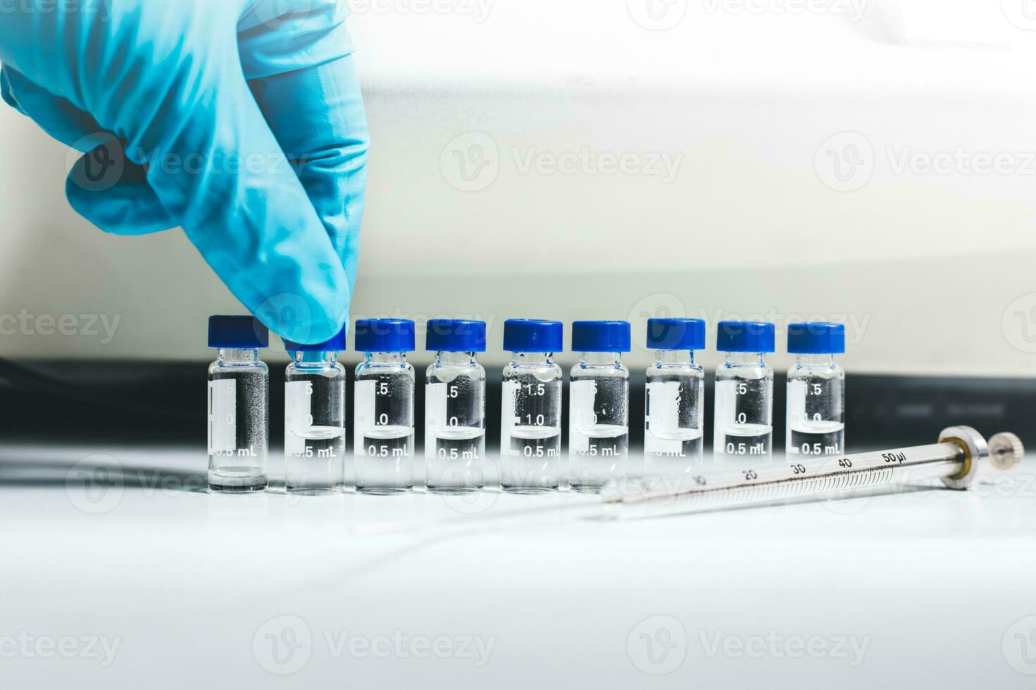 Hand of the scientist pick up the vial of sample solution to analyze by Liquid Chromatography mass spectrometry LC-MS instrument in the laboratory. The LC-MS is used for scientific research. photo