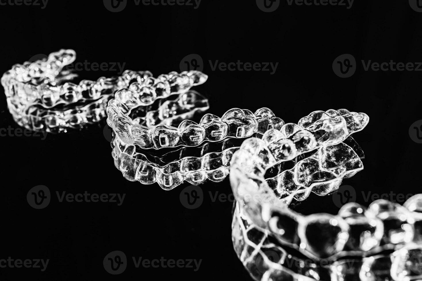 Invisible aligners retainers of teeth lie on the mirror on a black and white photograph photo