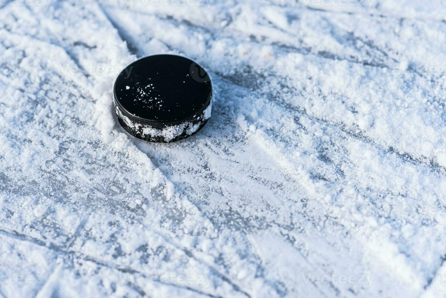 black hockey puck lies on ice at stadium photo