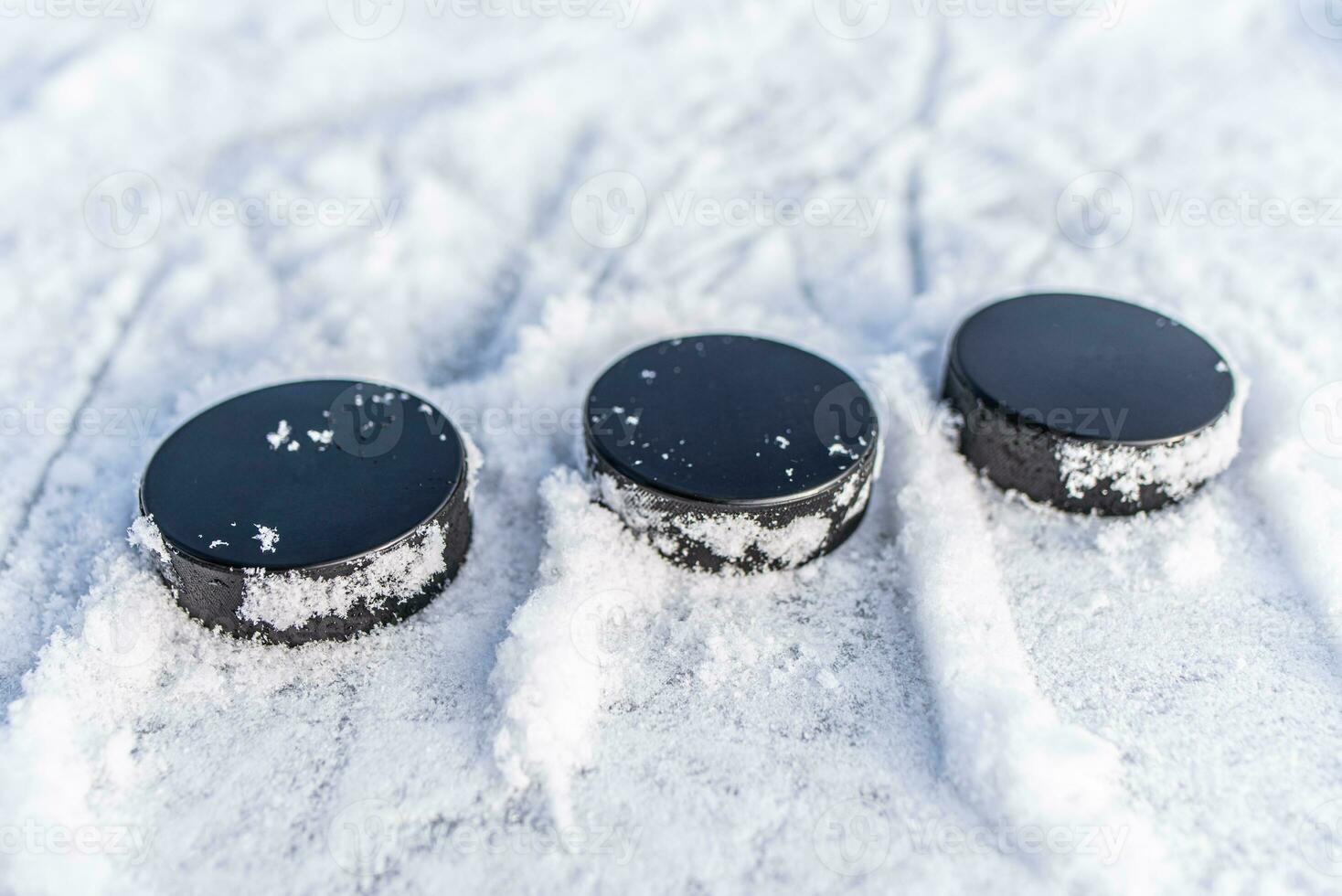 black hockey pucks lies on ice at stadium photo