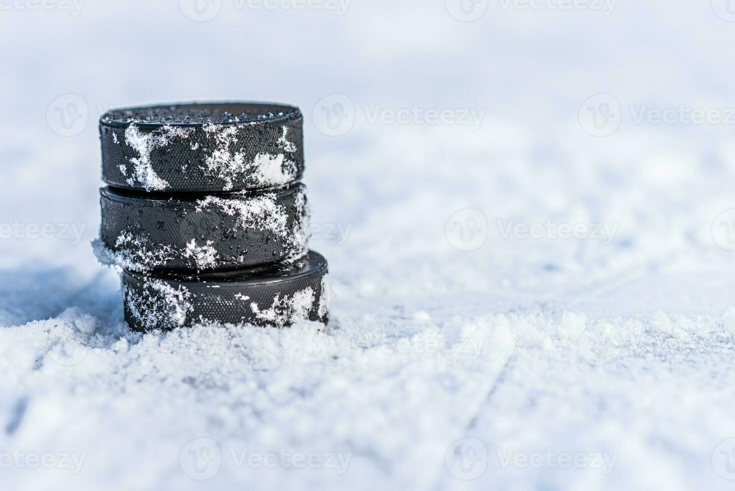 black hockey pucks lies on ice at stadium photo