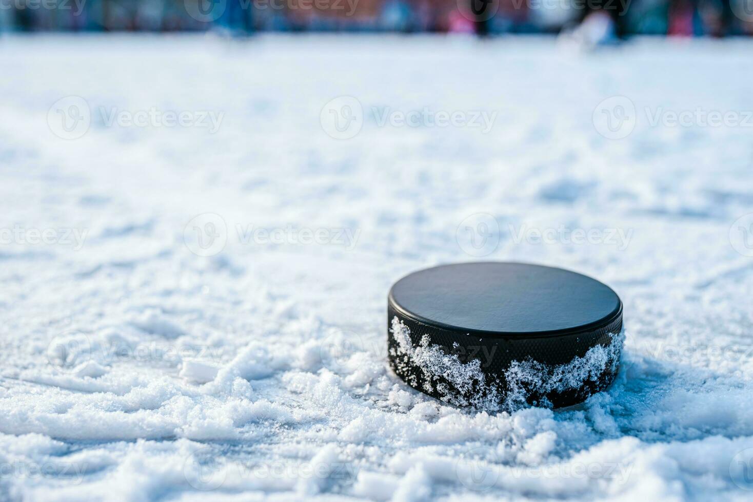 black hockey puck lies on ice at stadium photo