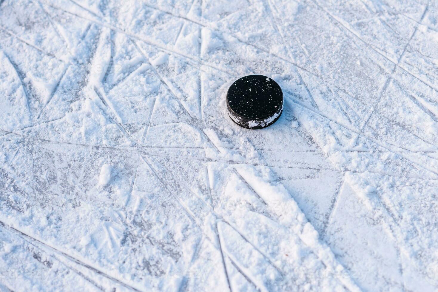 black hockey puck lies on ice at stadium photo