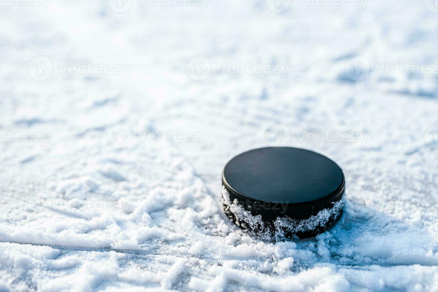 black hockey puck lies on ice at stadium photo