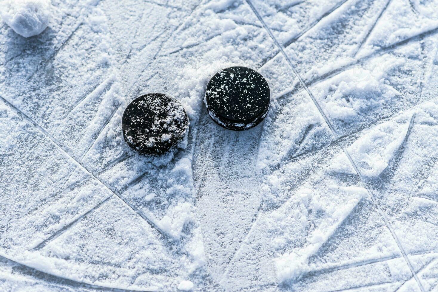 black hockey pucks lies on ice at stadium photo