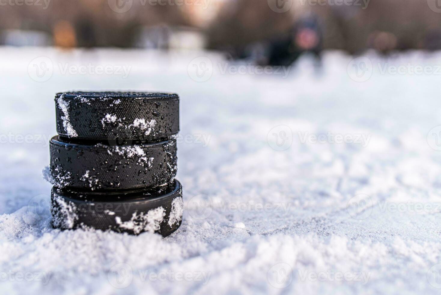 black hockey pucks lies on ice at stadium photo