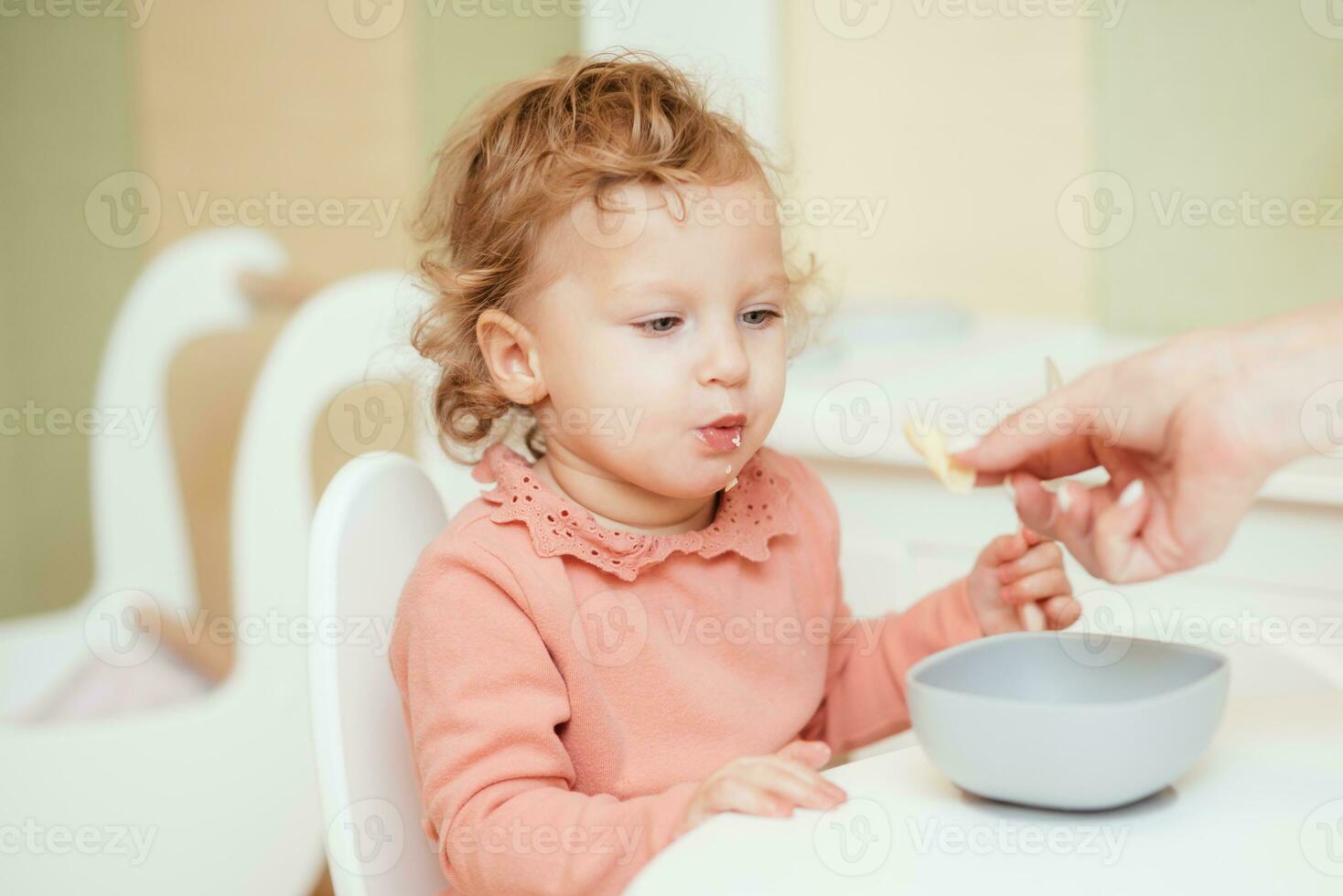 Little baby eats pasta in the children's kitchen photo