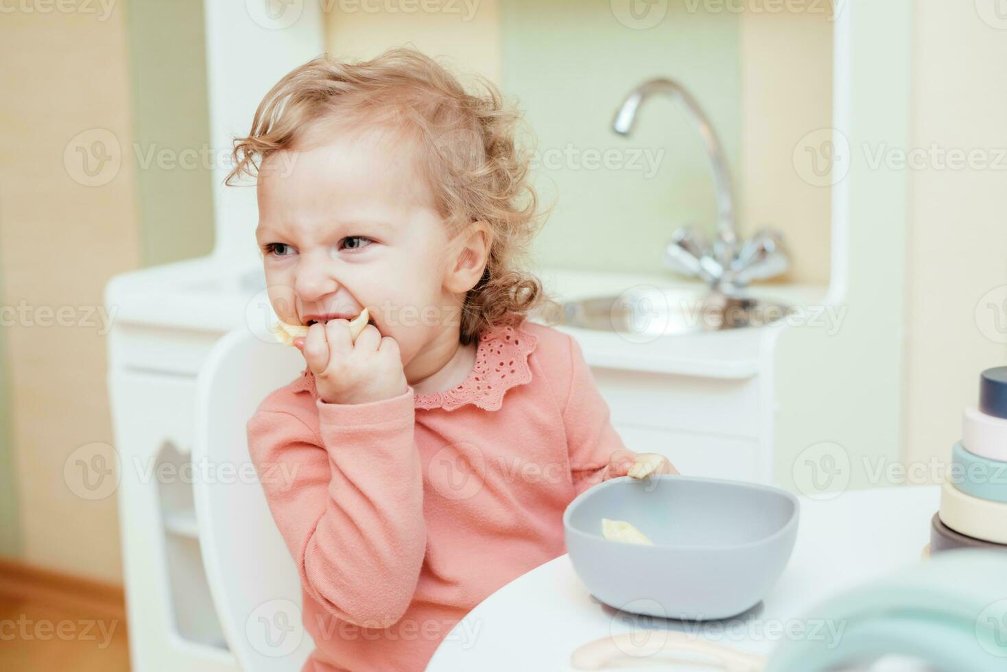 Happy little girl eating pasta in kindergarten photo