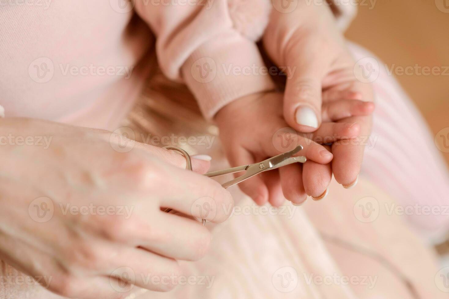 Caring mother cuts fingernails to little baby photo