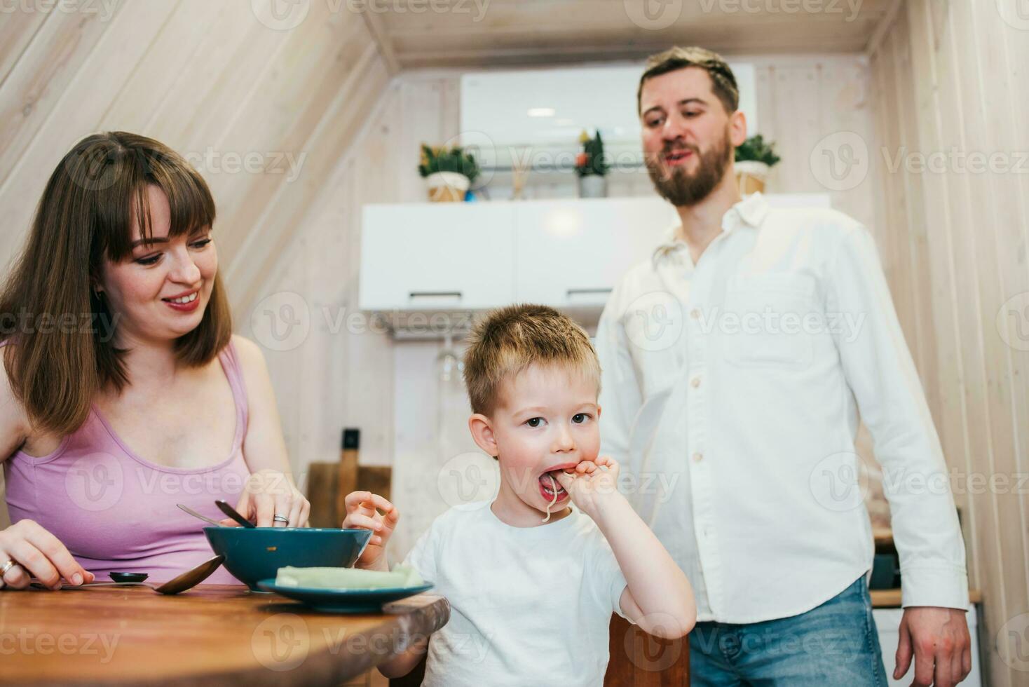 Happy family eating pasta in the kitchen photo