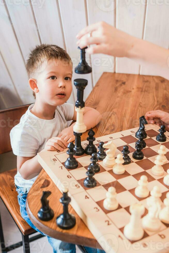 Little boy playing chess at home at the table photo