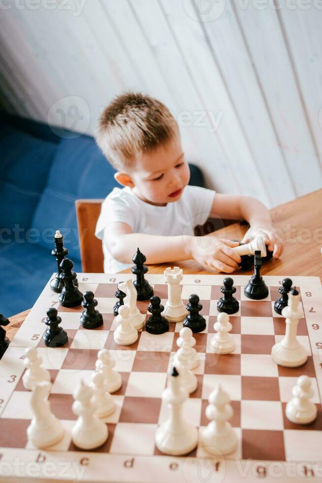 pequeño chico jugando ajedrez a hogar a el mesa foto