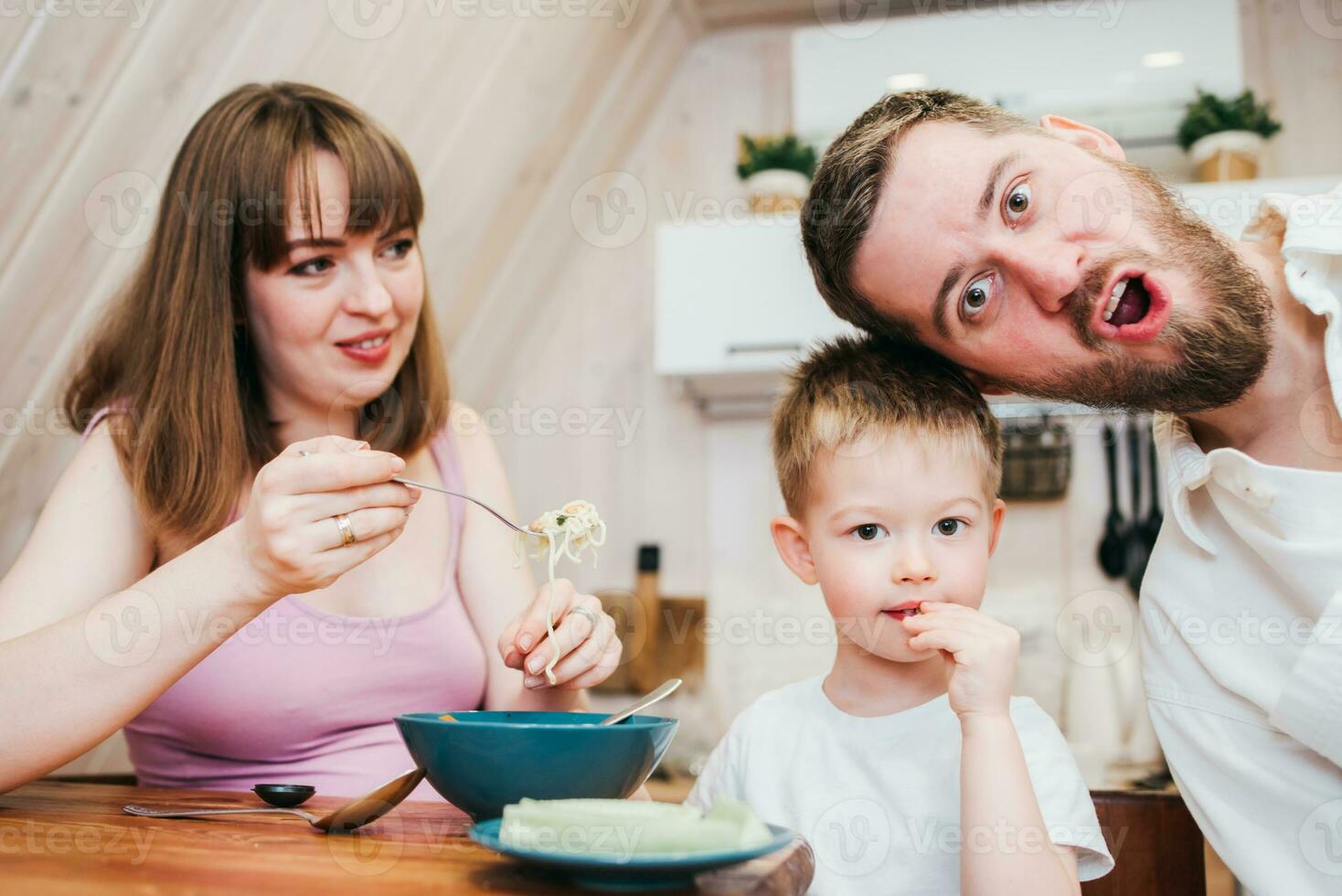 Happy family eating pasta in the kitchen photo