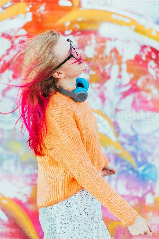 Portrait of a young laughing girl with braces listening to music in headphones in the summer on the street photo