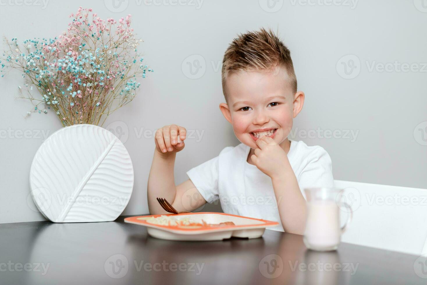 riendo chico come delicioso pasta a el mesa en el cocina foto