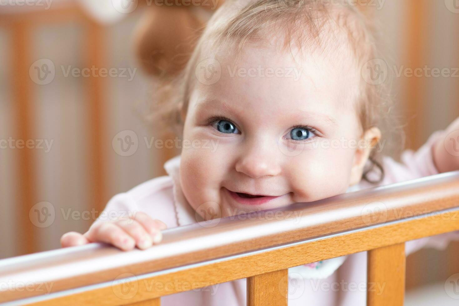 Portrait of a laughing baby who is standing in a crib photo