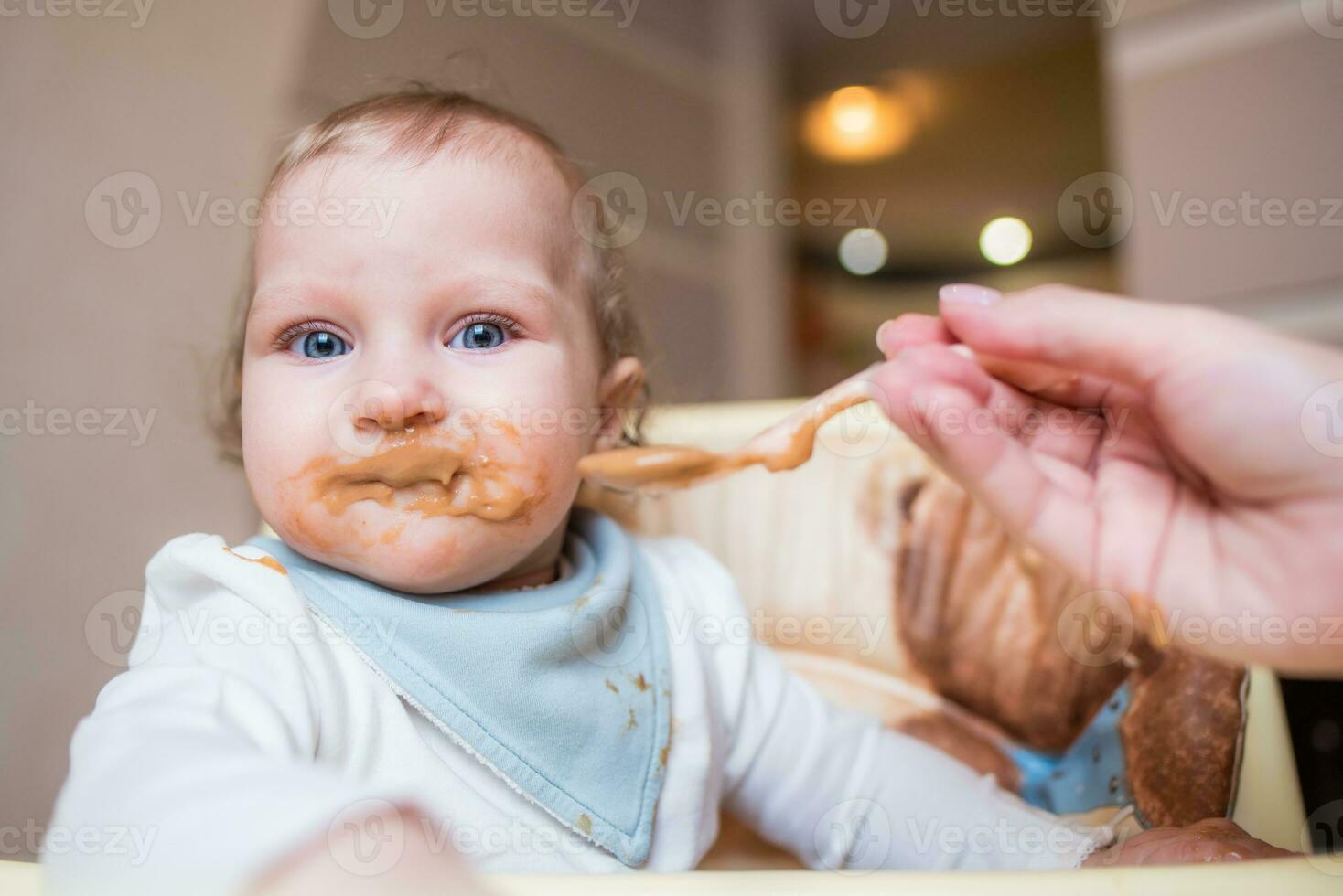 contento madre alimentación su linda pequeño hija Fruta puré desde un cuchara. primero comida foto