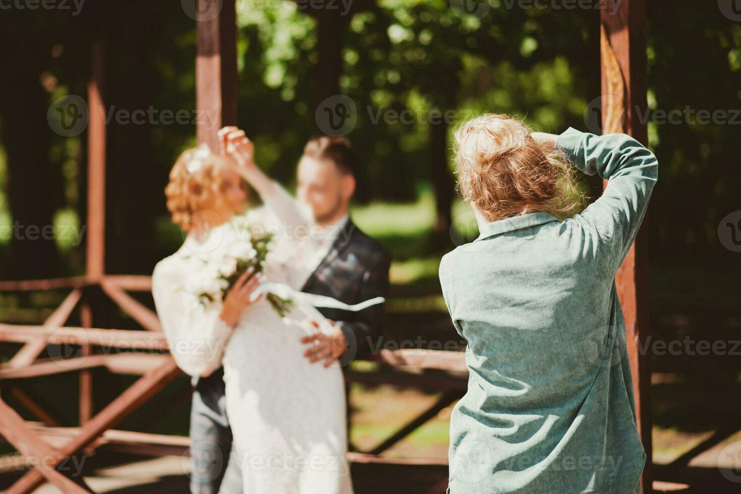 A wedding photographer photographs a couple in nature on a sunny day photo