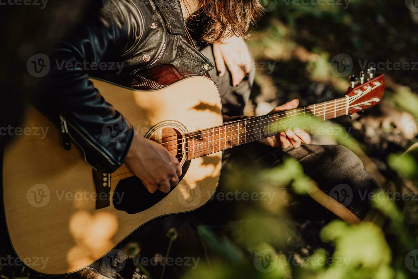 Musician man playing guitar at sunset close-up photo