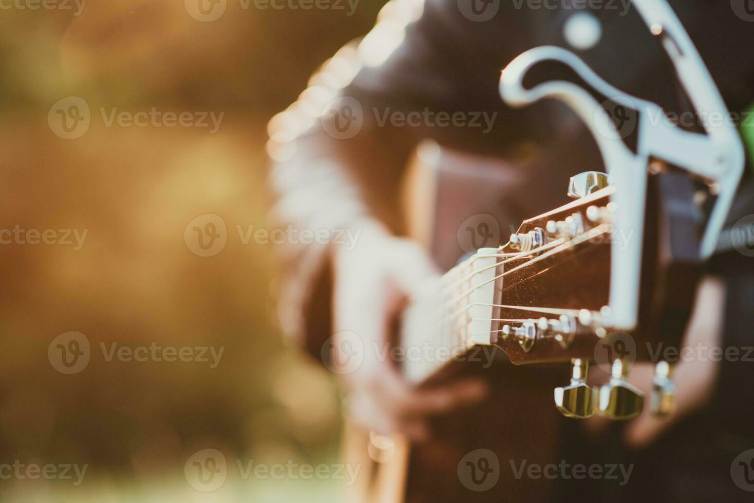 Musician man playing guitar at sunset close-up photo