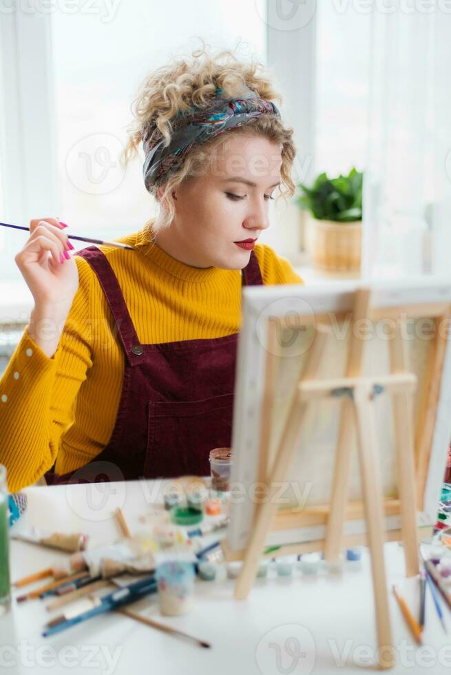 Beautiful woman artist paints on canvas at home photo