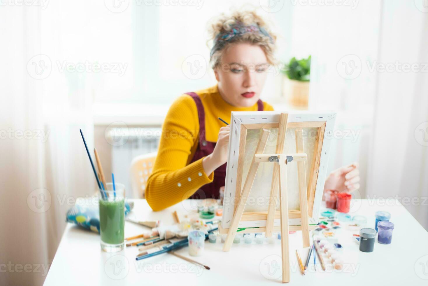 Beautiful woman artist paints on canvas at home photo