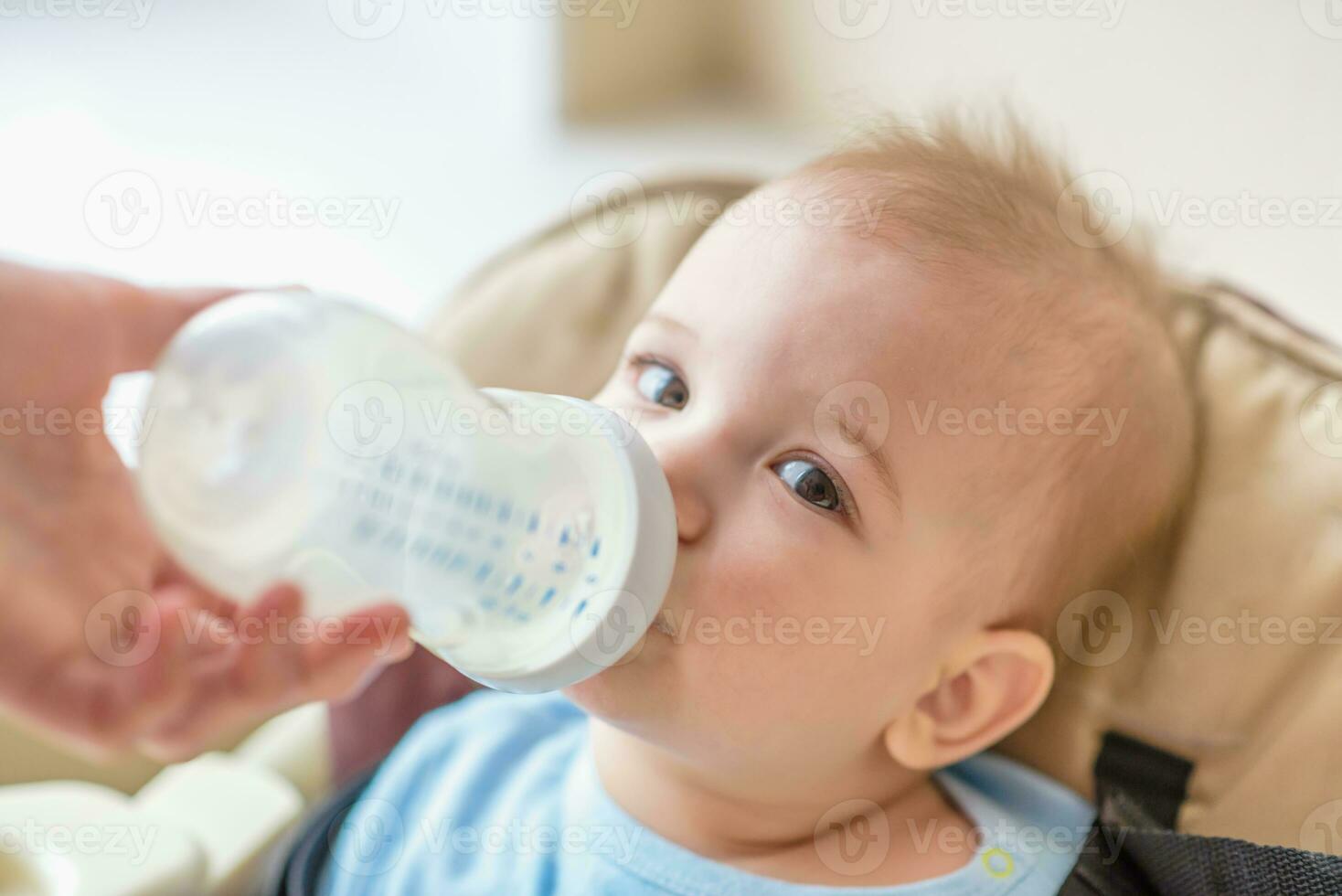 Mom is feeding her baby a bottle of milk photo