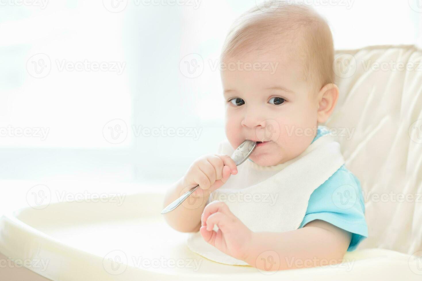 baby holding a spoon in his mouth photo