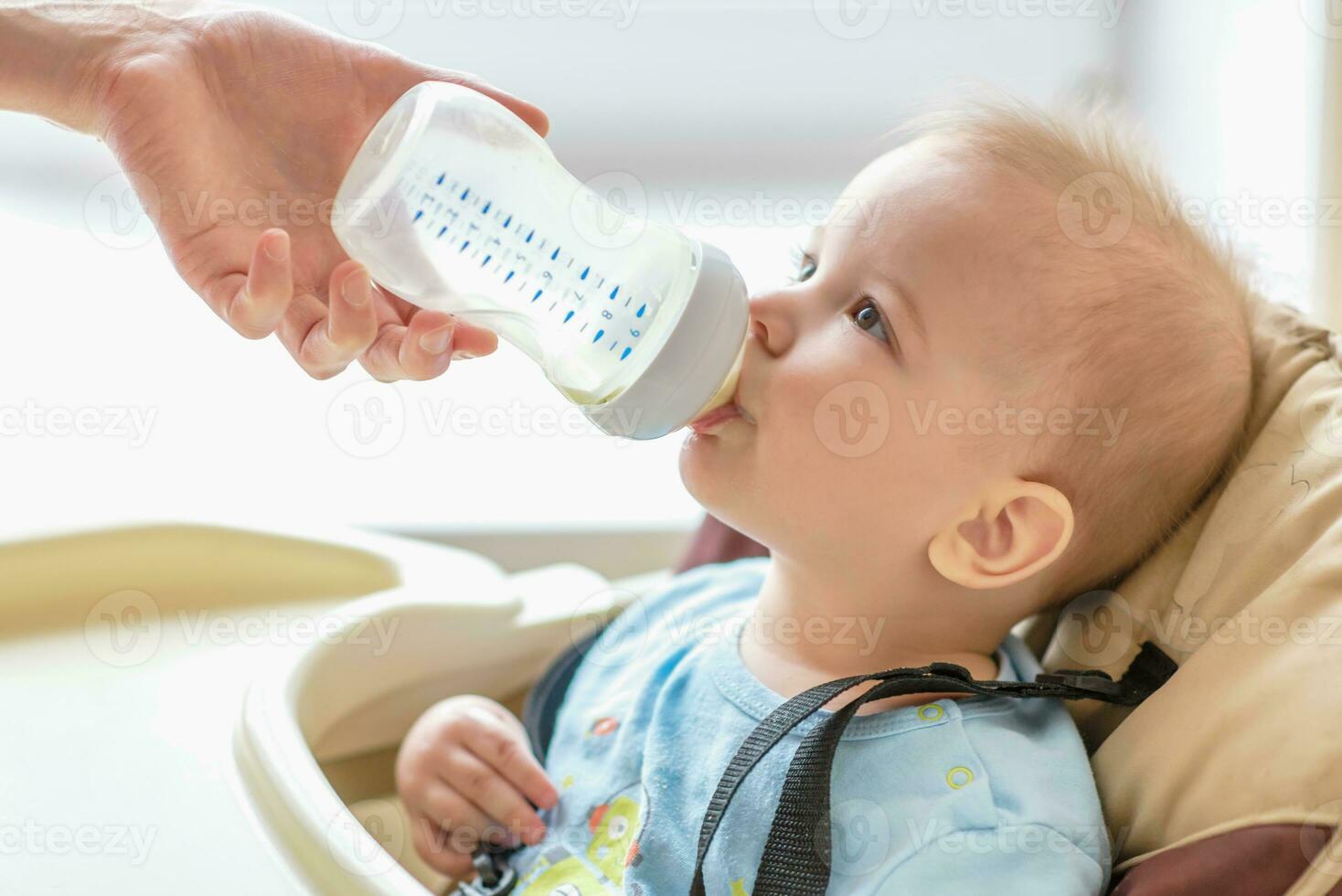 mamá es alimentación su bebé un botella de Leche foto