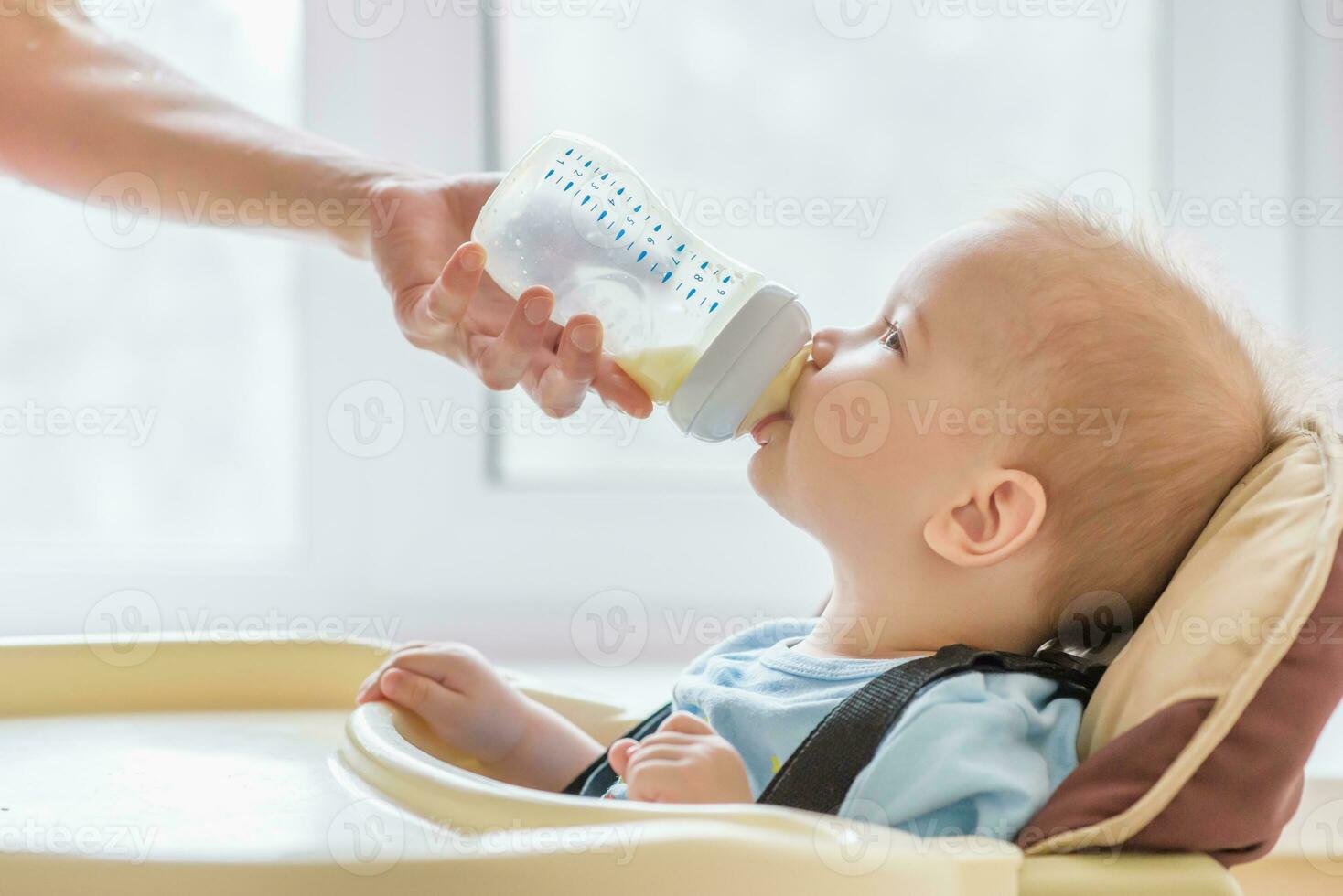 mamá es alimentación su bebé un botella de Leche foto