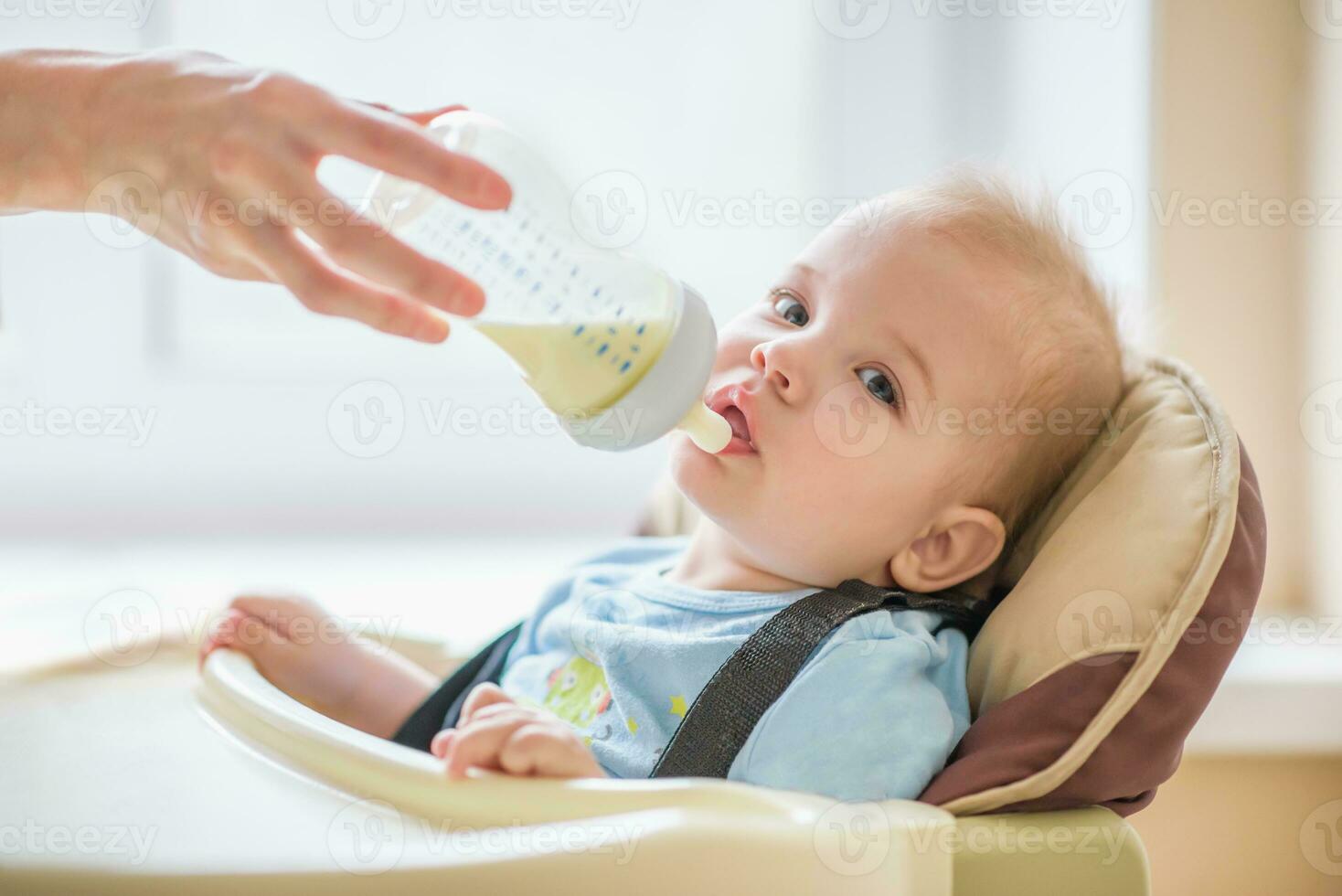 Mom is feeding her baby a bottle of milk photo