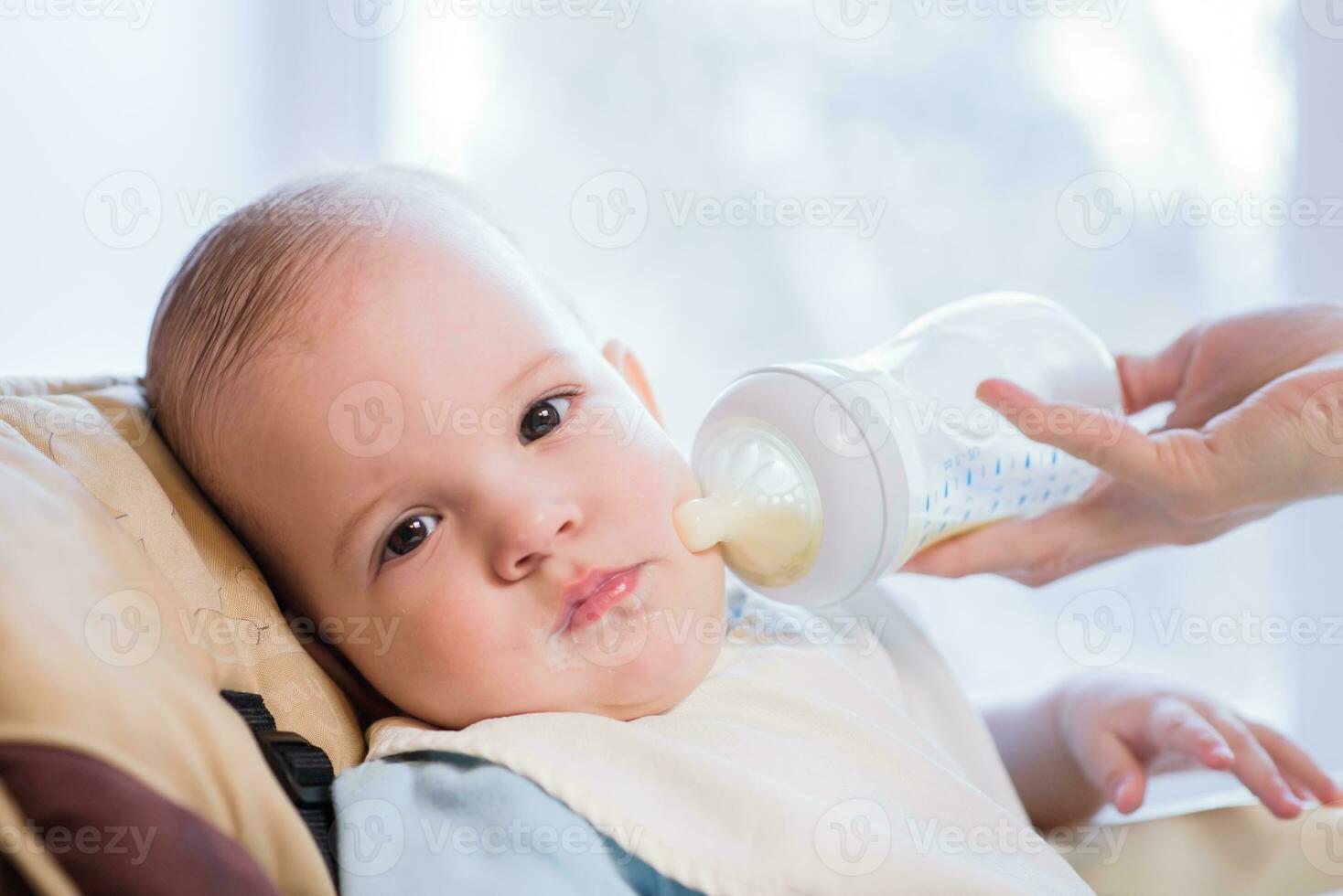 Mother feeds baby from a bottle of milk photo