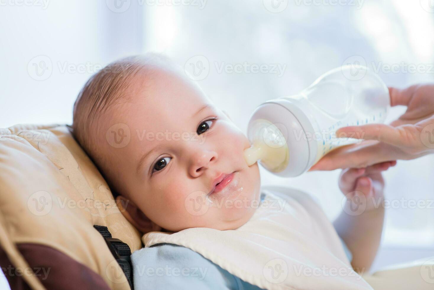 Mother feeds baby from a bottle of milk photo