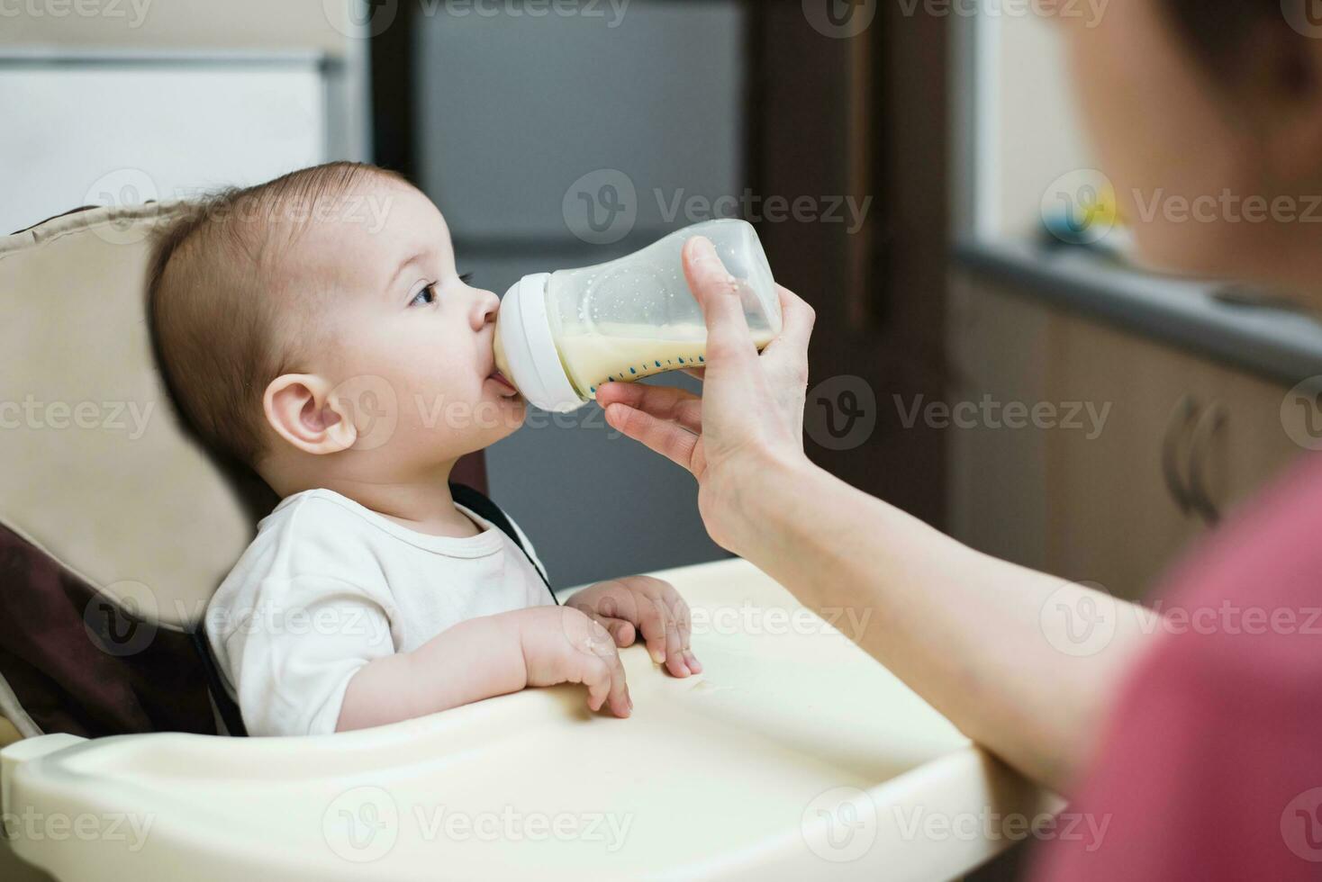 Mother feeds baby from a bottle of milk photo