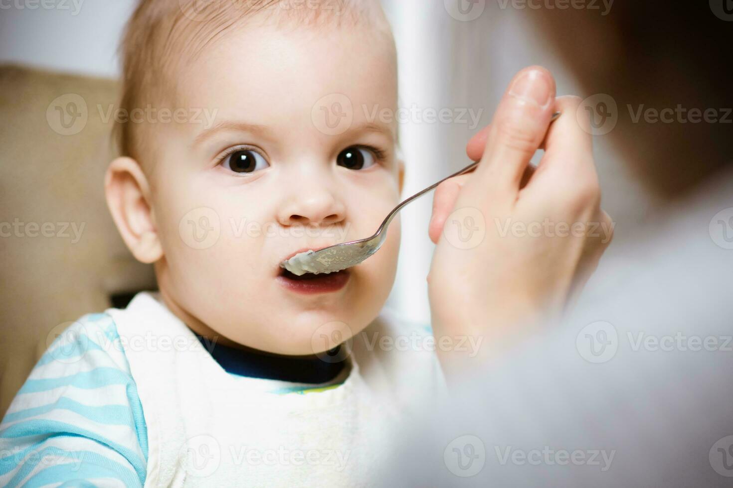 Mother gives baby food from a spoon photo